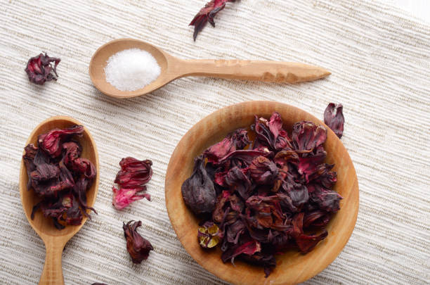 top view at wooden bowl and spoon of dry hibiscus petals on linen cloth background - medicine closed antioxidant close to imagens e fotografias de stock