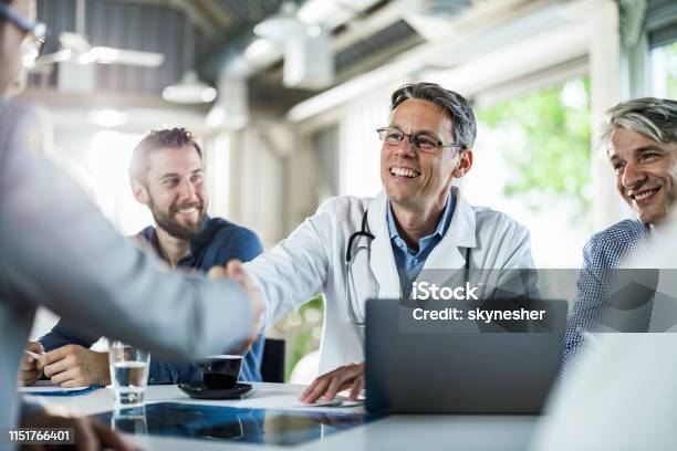 Glückliche Ärztin Schüttelt Hände Mit Einem Geschäftsmann Auf Einem Treffen Im Büro Stockfoto und mehr Bilder von Arzt