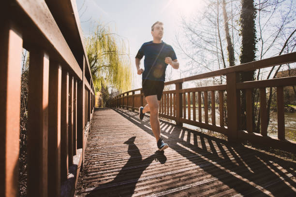 istock Male runner running in a city park over a bridge 1151769992