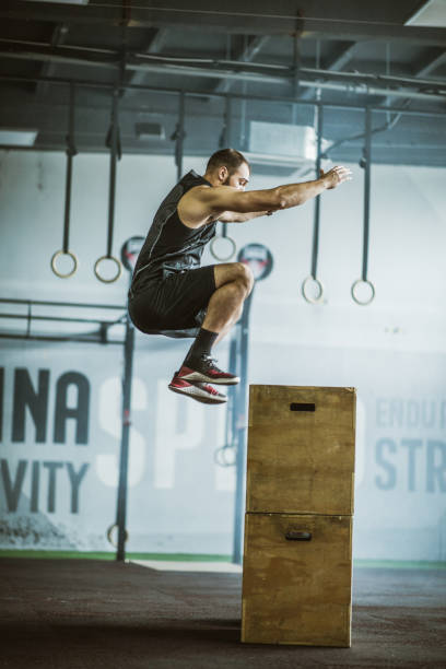 istock Athletic man jumping on a crate while having sports training in a gym. 1151772077
