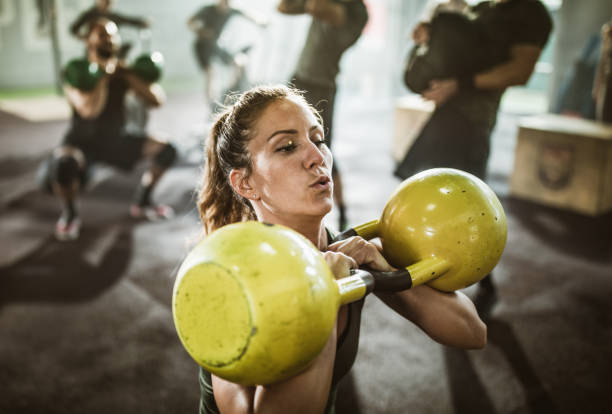 istock Determined woman exercising with kettle bells on cross training in a gym. 1151772113