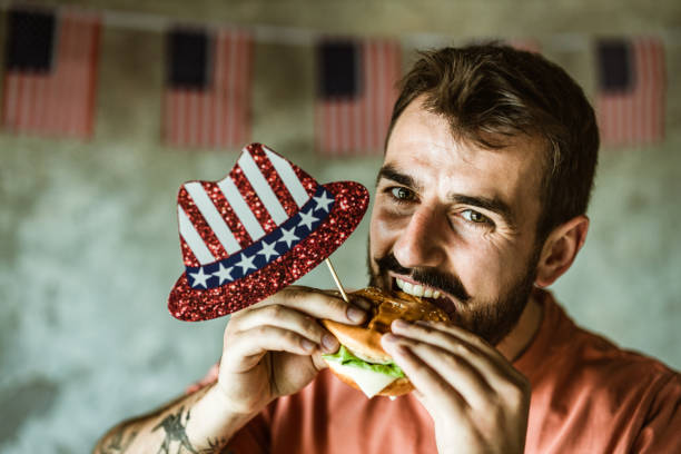 istock Young happy man eating burger on Independence day. 1151778077