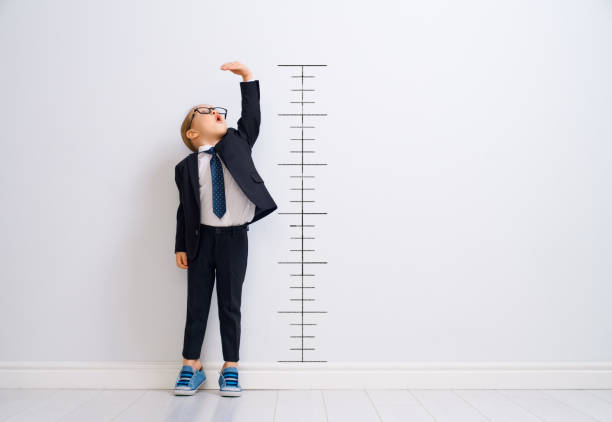 Kid is measuring the growth Little child is playing businessman. Kid is measuring the growth on the background of wall. Smart power concept. anticipation stock pictures, royalty-free photos & images