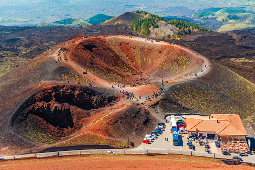 Stunning view at the volcanic crater and groups of tourists walking around it. Mount Etna, Sicily, Italy.