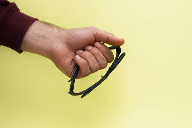 istock Black 3D glasses in hand isolated on yellow background. 1151781713