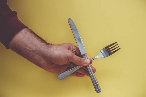 istock Hand with knife and fork on a yellow background. 1151781795