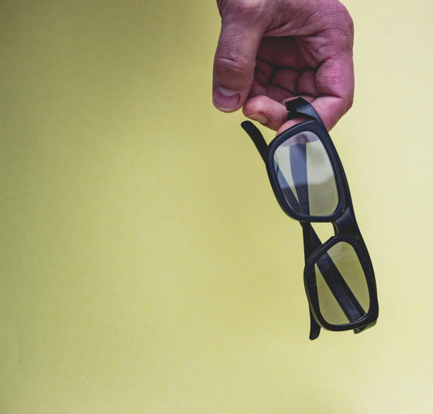 istock Black 3D glasses in hand isolated on yellow background. 1151781822