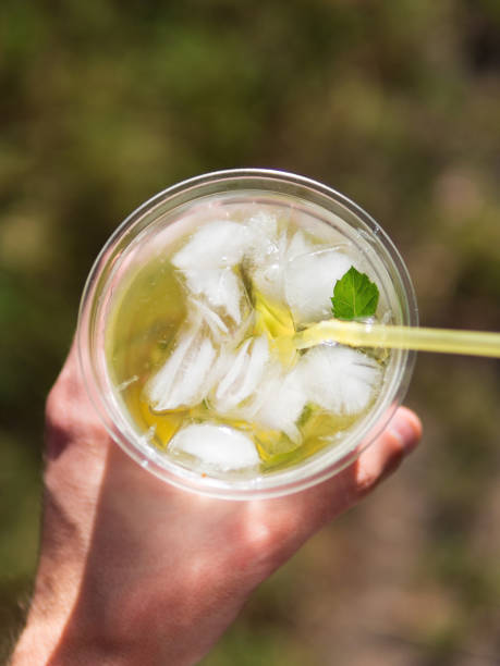 istock Lemonade in a plastic mug in hand close-up 1151782823
