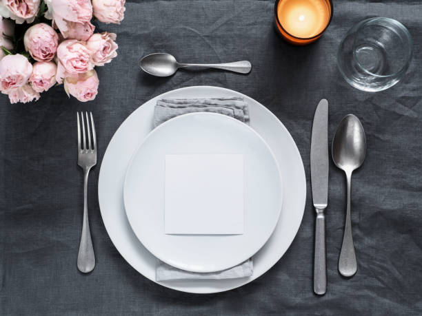 Beautiful wedding table setting mock up Menu, wedding invitation mock up. Beautiful table setting on gray linen tablecloth. Festive table setting for wedding dinner with pink spray roses and cabdle. Holiday dinner, white plates. Copy space beautiful table setting stock pictures, royalty-free photos & images