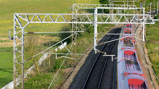 uk train railroad next to rapeseed field in bloom day view in england. spring railway landscape.