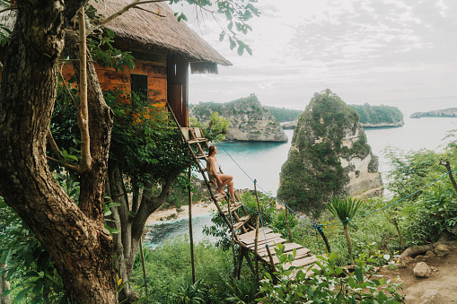 Vista panorámica de la mujer cerca de la casa del árbol cerca del mar en Nusa Penida photo