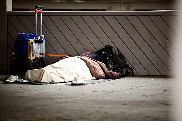 Front view of homeless men bed and an orange blanket. Belongings in the front.