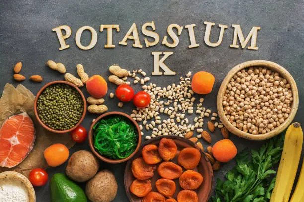 Photo of Foods rich in potassium, salmon, legumes, vegetables, fruits on a dark background. Healthy food concept,avitaminosis prevention. Top view, flat lay.