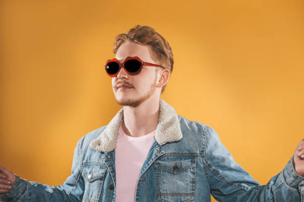 istock Young man in lip shaped sunglasses on yellow background 1151794623