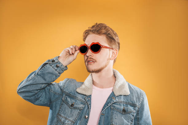 istock Young man in lip shaped sunglasses on yellow background 1151794640