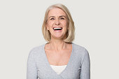 Headshot happy aged female laughing posing on grey studio background