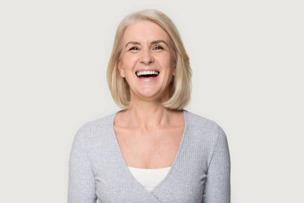 headshot happy aged female laughing posing on grey studio background - women female cheerful ecstatic imagens e fotografias de stock