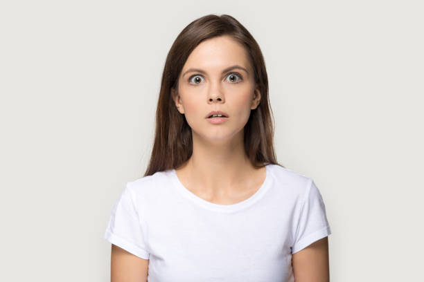 scared girl looking at camera posing over grey studio background - huge eyes imagens e fotografias de stock