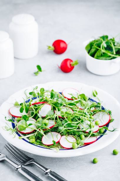 istock Fresh green pea shoots salad with radishes. 1151798291