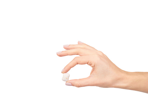 This close-up photograph features a 101 year old woman holding prescription medication pills and Vitamin Supplements in her hand. She has a bandage on her thumb. The senior adult is seated in the comfort of her domestic living room. Handling and taking pills or capsules can be difficult for individuals suffering from arthritis. \n\nThe photograph captures the real-life choices and healthcare practices of this one woman as she has crossed the milestone of living beyond 100 years. The image shows the importance of medicine and healthcare in maintaining a long and healthy life.