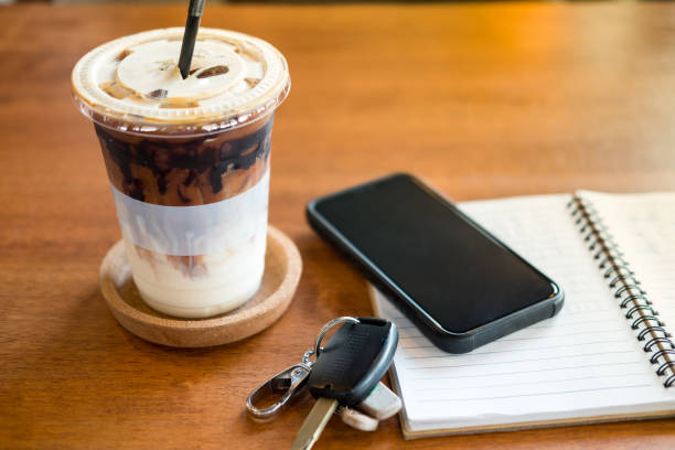 Office desk with cup of iced coffee and phone, car key on notebook. Freelancer concept Office desk with cup of iced coffee and phone, car key on notebook. Freelancer concept car keys table stock pictures, royalty-free photos & images