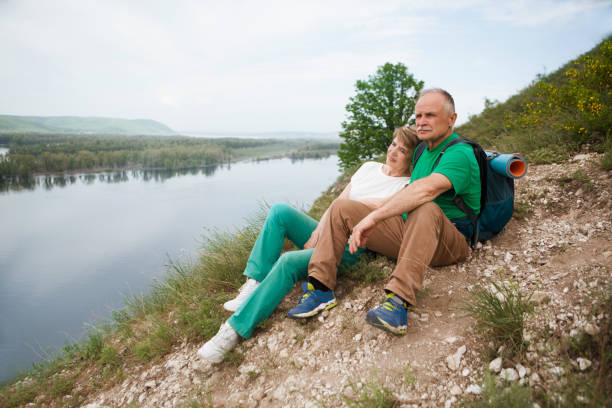 elderly couple with backpacks sits on the mountain. senior couple walking in nature - couple walking old middle imagens e fotografias de stock