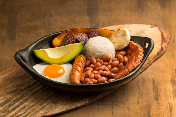 bandeja paisa, типичное блюдо в регионе антиокенья в колумбии. он состоит из чичаррон (жареный свиной живот), черный пудинг, колбаса, арепа, фасоль,  - bandeja paisa стоковые фото и изображения