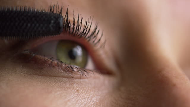 Close-Up of a Young Caucasian Woman Using a Mascara Wand to Apply Mascara Makeup to Her Eyelashes