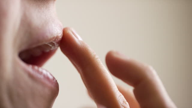 Close-Up of a Caucasian Woman in Her Thirties Using Her Finger to Apply Hydrating Lip Balm to Her Lips