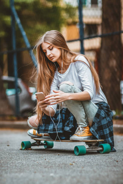 istock Female Skateboarder is Using a Mobile Phone in the Street 1151811351
