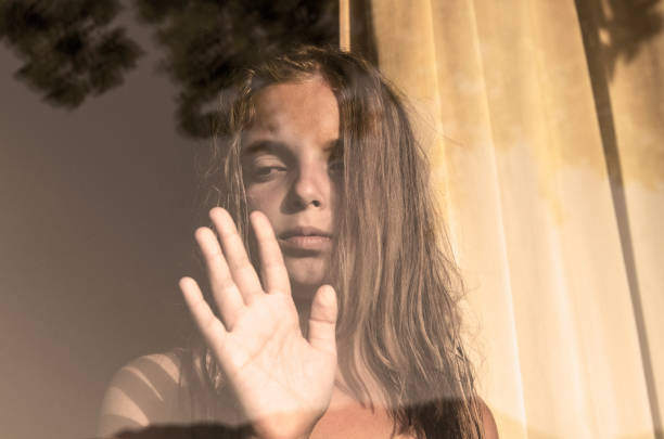 Anxious child waiting near window glass with reflection