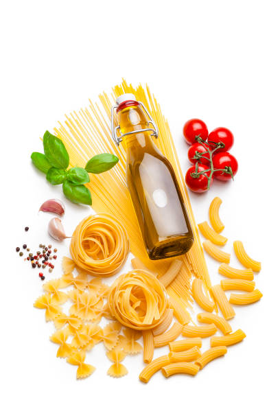High angle view of ingredients for cooking Italian pasta isolated on white background. The composition includes various types of raw pasta like spaghetti, fettuccine, rigatoni and tie bow pasta as well as olive oil, ripe tomatoes, basil, garlic cloves and peppercorns. Predominant color is yellow. High key DSRL studio photo taken with Canon EOS 5D Mk II and Canon EF 100mm f/2.8L Macro IS USM.