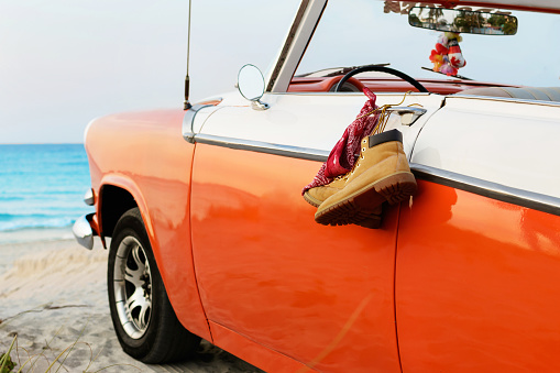Retro car with tied boots and bandana to a door handle on the beach