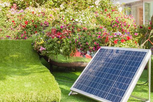 Solar cell in back or front house yard with trees and flowers warm sunny spring or summer day. natural environment concept clean innovation technology energy - image