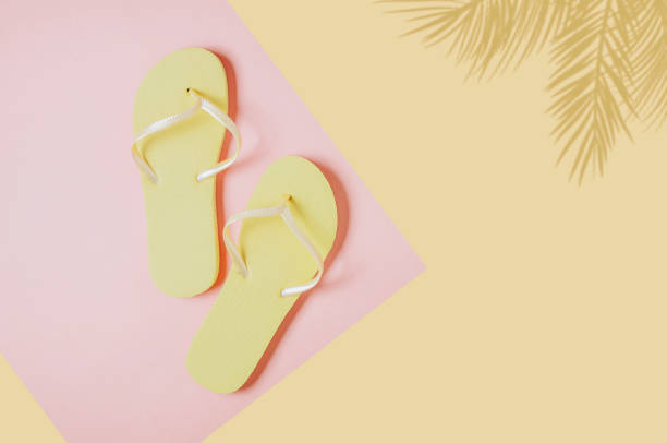 istock Yellow flip-flops on pink-yellow background. Space for text or design 1151822051