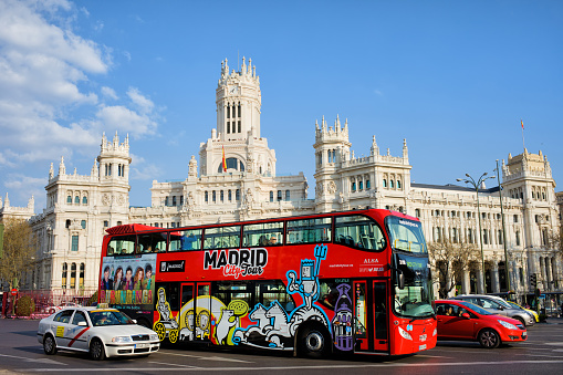 Madrid, Spain -  March 28, 2012: city center with double-decker sightseeing tour bus on Plaza de Cibeles with Cybele Palace in the background.
