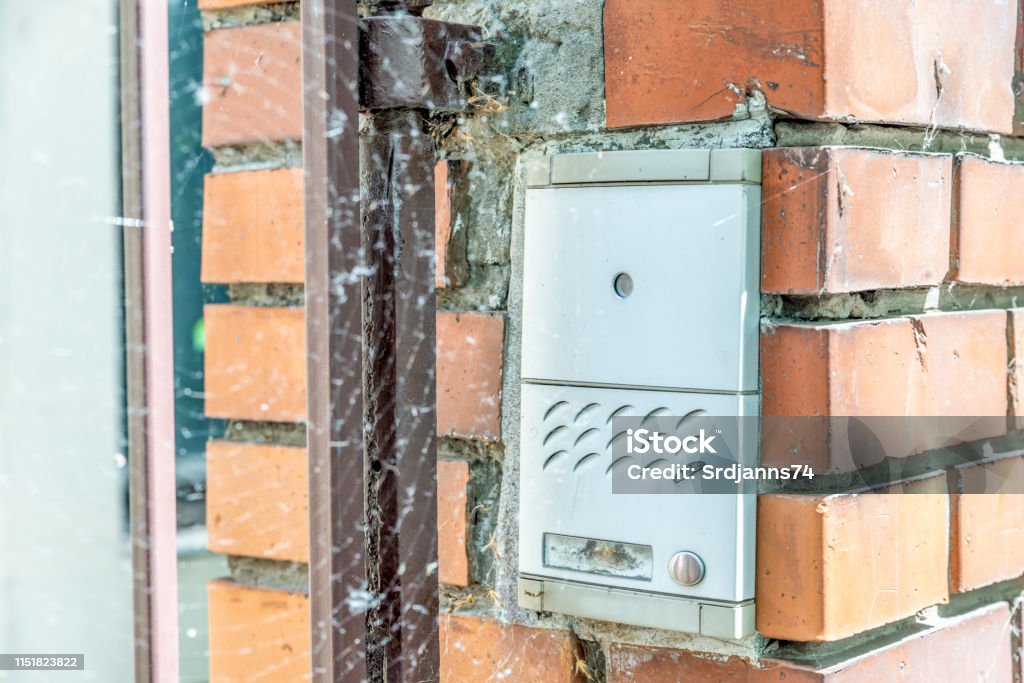 Metal electric device ring intercom bell with two buttons or dials for doorbell and speaker on the stone wall of the house exterior Accessibility Stock Photo