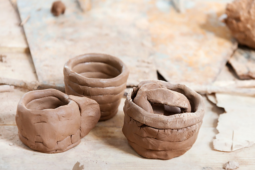 Handmade raw clay ceramic brown cup and bowls on the rustic table. Hobbies and interests craft handmade and side hustles at home concept - Image