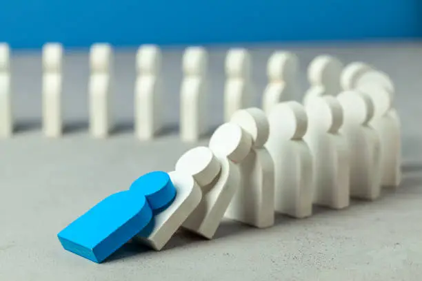 Domino effect in business. One businessman leader falls and brings down other figures of employees. System disruption