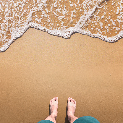 Pies de pie en la arena del mar y la ola con el espacio de copia, vacaciones en la playa del océano, vacaciones de verano. photo