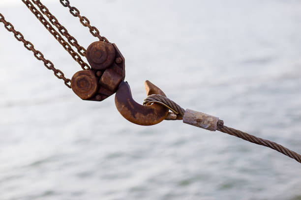 Swivel joint and connection with a steel cable when installing the structures outdoor. Rusty Sling With Hook . Hook construction crane with slings near sea.