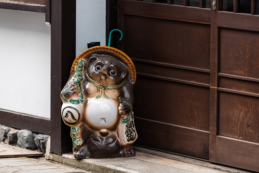 Takayama, Japan - April 6, 2019: Gifu prefecture in Japan with traditional wooden houses on alley street road and statue decoration of Tanuki