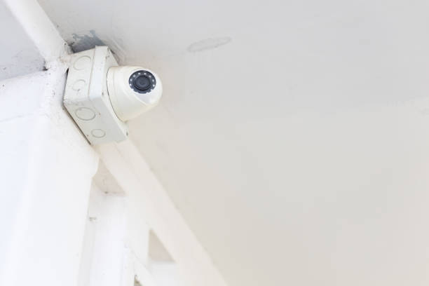 istock closeup of closed circuit television camera or CCTV and box control on white concrete ceiling. 1151830955