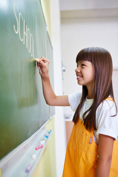 istock Smiling girl writing on chalkboard in class 1151837646