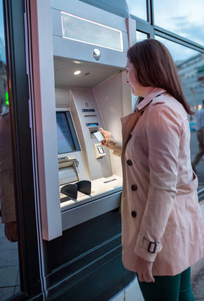 istock young woman inserting a credit card to ATM 1151839043