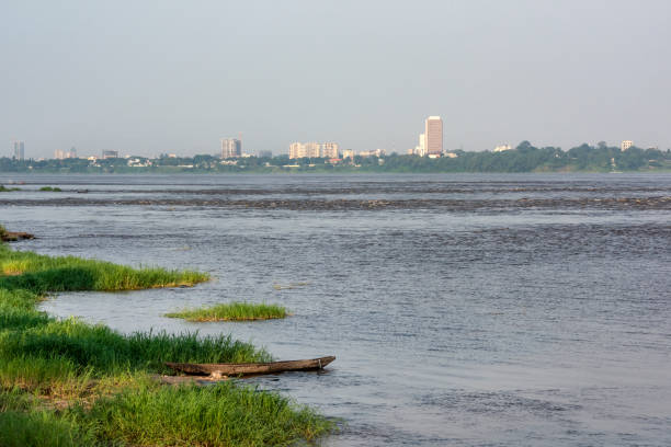 Skyline of Kinshasa on Congo River, seen from Brazzaville A typical dugout canoe (pirogue) on Congo River, seen from Brazzaville, the capital of Republic of Congo. In the background the Skyline of Kinshasa, the capital of the Democratic Republic of Congo. The river is the border in between these to African countries. kinshasa stock pictures, royalty-free photos & images