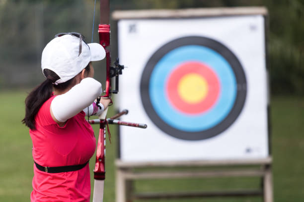 Female athlete practicing archery in stadium Portrait of female athlete practicing archery in stadium. archery photos stock pictures, royalty-free photos & images