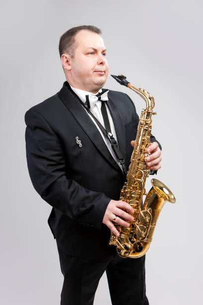 istock Man with Saxophone in Suite Posing Against White Background. Vertical Image Orientation 1151844109