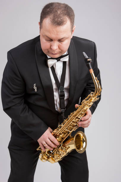 istock Caucasian Man in Suite with Saxophone. Posing Against White. Vertical Image 1151844129