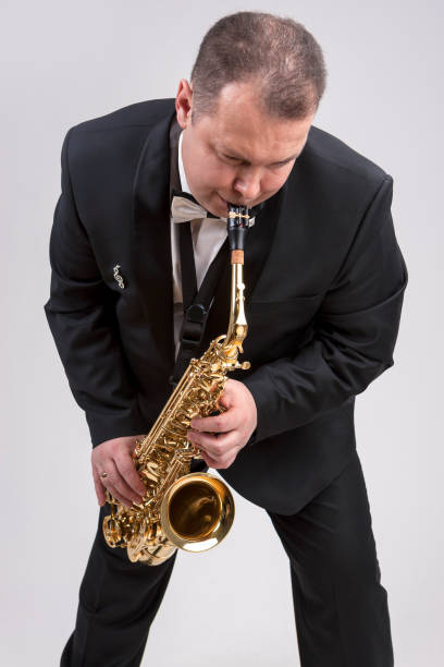 istock Caucasian Man in Suite Playing the Saxophone. Posing Against White. Vertical Image Orientation 1151844170